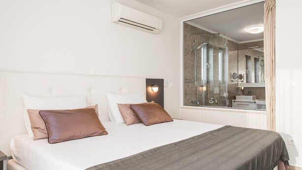 Een moderne hotelkamer met een groot bed, een douchecabine van glas en uitzicht op de badkamer.