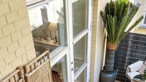 Een terras met een bamboebeschutting, potplanten en een wit beklede zithoek.