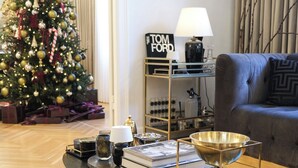 Een woonkamer met een kerstboom, boeken, een lamp en een bank.