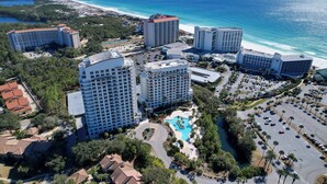 Eine Vogelperspektive auf einen Hotelkomplex mit mehreren Hochhäusern, einem zentral gelegenen Swimmingpool und direktem Strandzugang.