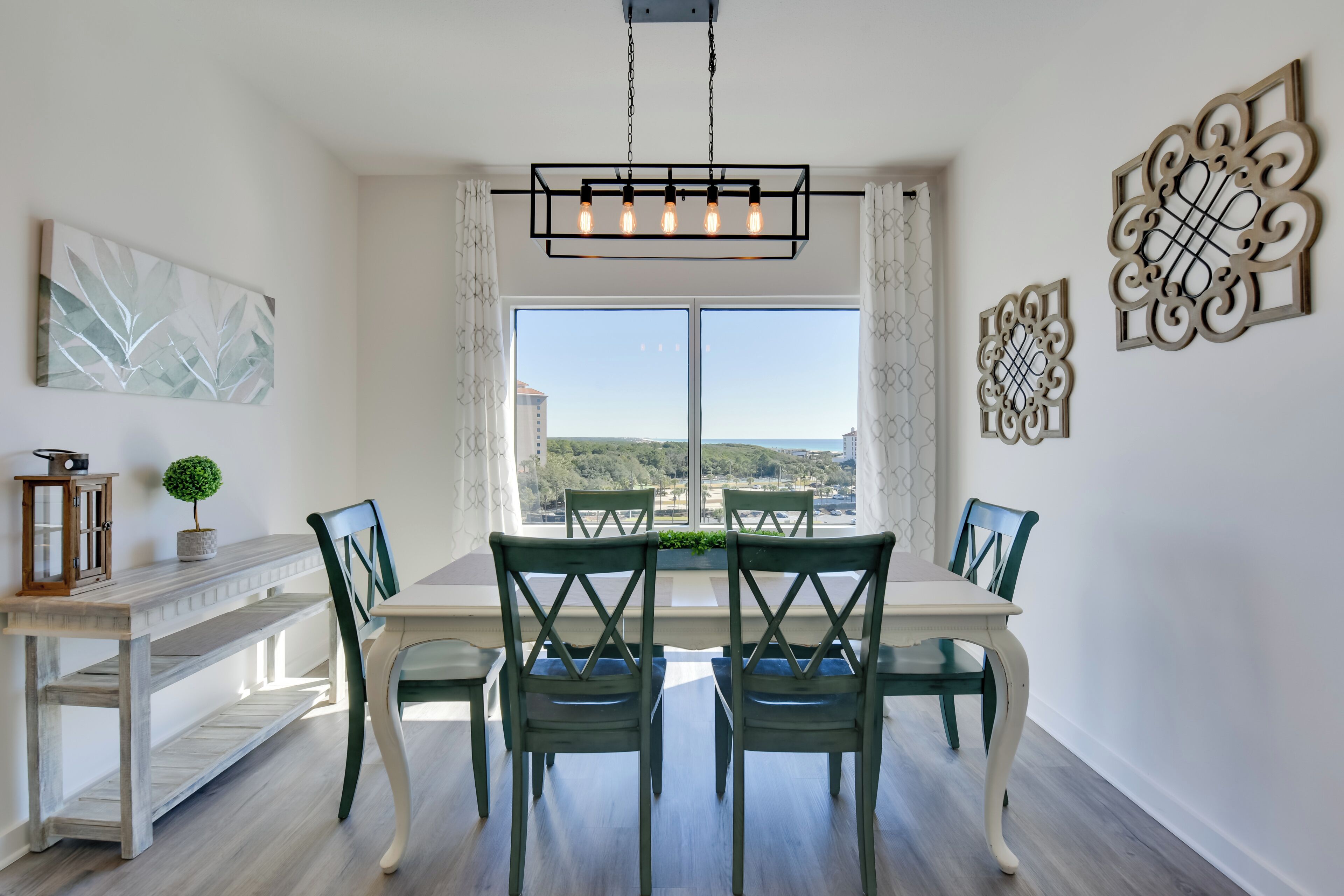 A dining area with a table and chairs, a hanging light fixture, and decorative wall art.