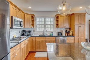 A modern kitchen with wooden cabinets, stainless steel appliances, and a large window.