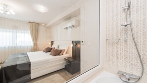 A modern hotel room with a large bed, a glass shower enclosure, and a bathtub. - Sargas Suite 5 With Pool View (Novalja)