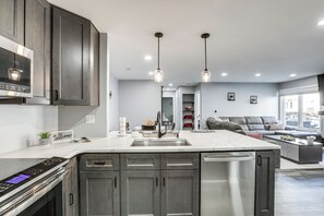A modern kitchen with dark cabinets, stainless steel appliances, and pendant lighting. - Easy Commute to Philly: Traveling Pros' Hub! (Levittown)