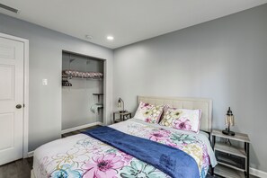 A bedroom with a bed, a nightstand, a lamp, a closet, and a door. - Easy Commute to Philly: Traveling Pros' Hub! (Levittown)