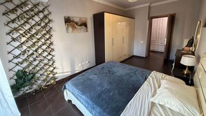 Et soveværelse med seng, garderobe og en plante på væggen.