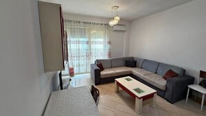 En moderne stue med en hjørnesofa, et lille bord og et fjernsyn.