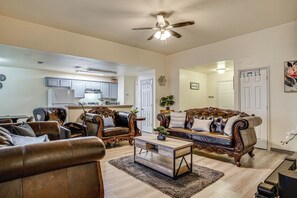 A living room with a brown leather sofa, a wooden coffee table, and a ceiling fan. - 16 Mi to Dallas Stadium! Home w/ Easy City Access (Dallas)
