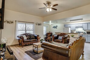A spacious living room with leather sofas, a wooden coffee table, and a ceiling fan. - 16 Mi to Dallas Stadium! Home w/ Easy City Access (Dallas)