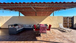 A rooftop patio with a covered seating area, a sofa, and a lounge chair. - Serena Stay Spacious 3BR Apartment (Puerto Peñasco)