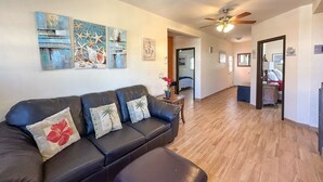 A spacious living area with a leather sofa, wooden flooring, and artwork on the walls. - Serena Stay Spacious 3BR Apartment (Puerto Peñasco)