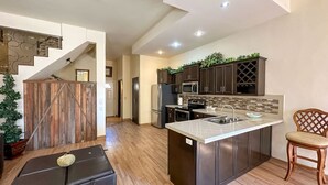 A modern kitchen with dark cabinets, stainless steel appliances, and a large island with a sink. - Serena Stay Spacious 3BR Apartment (Puerto Peñasco)