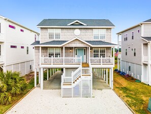 A two-story house with a front porch, a balcony, and a visible address number. - Stunning Views • 2 minute walk to beach • Charming Beach House (Ocean Isle Beach)