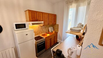 Una cocina compacta con microondas, estufa, pileta y alacenas de madera.