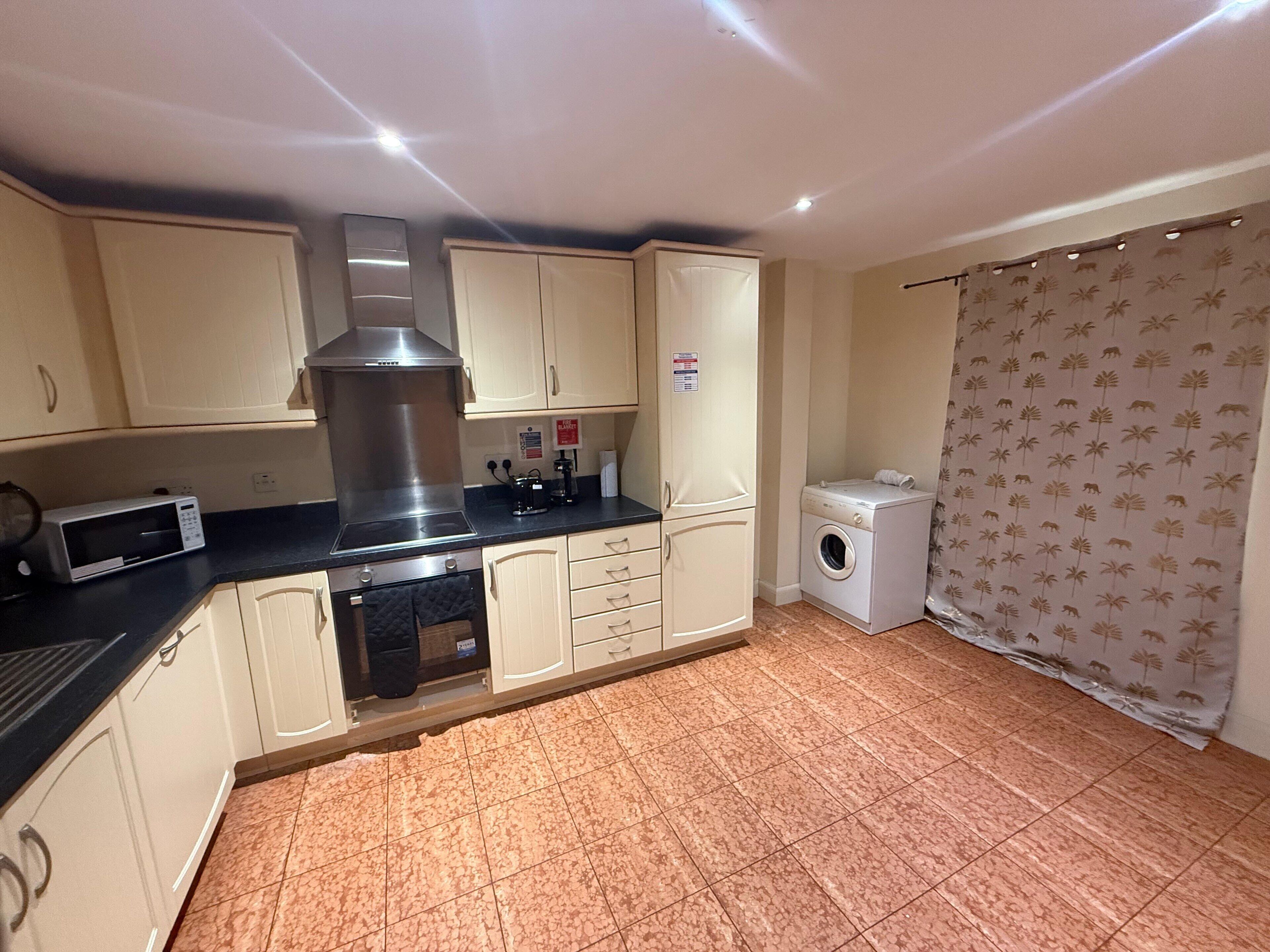 A compact kitchen with a microwave, stove, and washing machine.