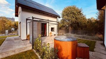 A modern house with a solar panel roof, a hot tub, and a covered patio area.