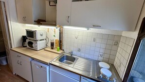 A compact kitchen with a dishwasher, a sink, and a stove. - Stay by the Hiking Trails (Mont-Dore)