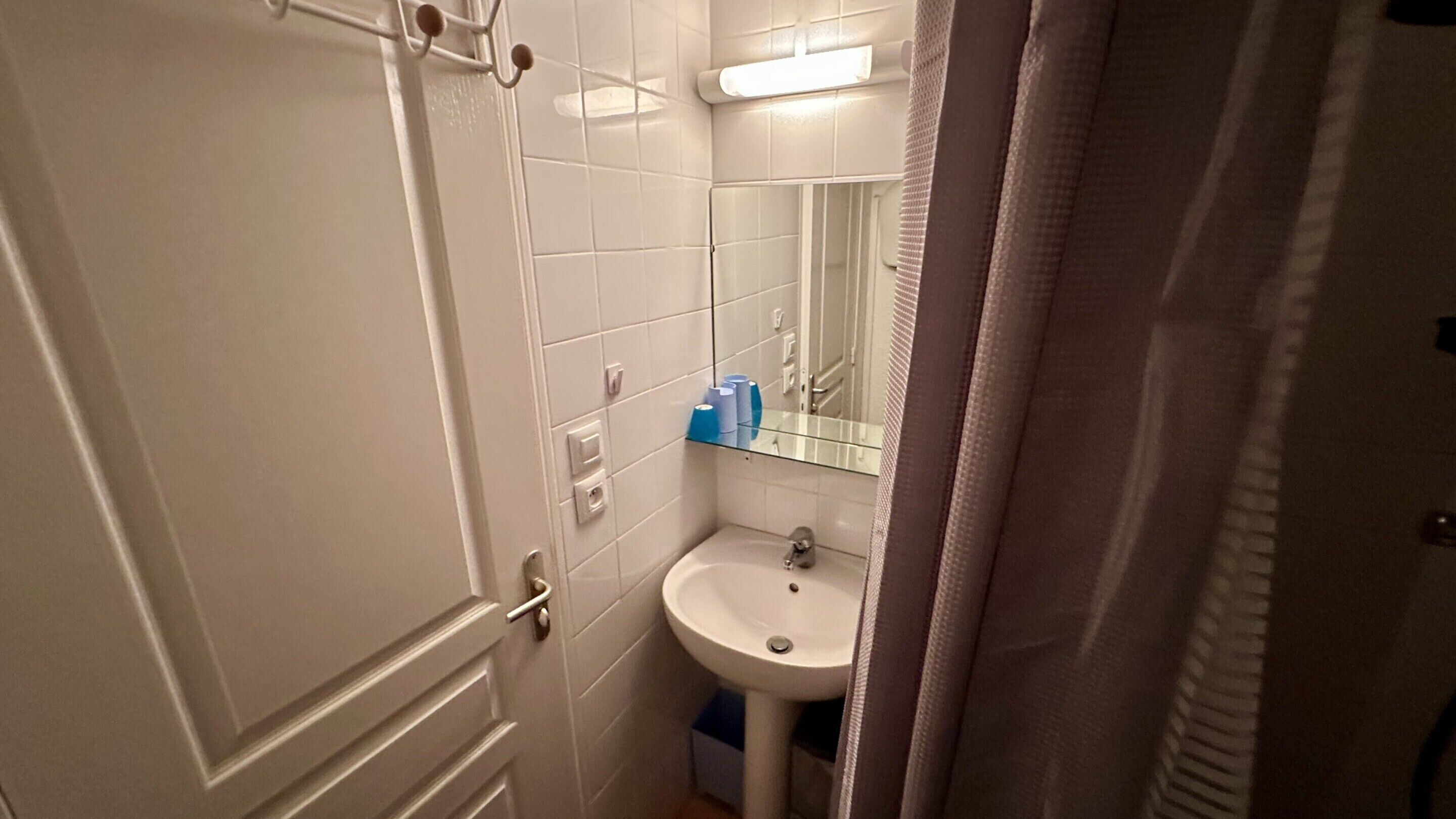 A bathroom with a white sink, a mirror, and a towel rack.
