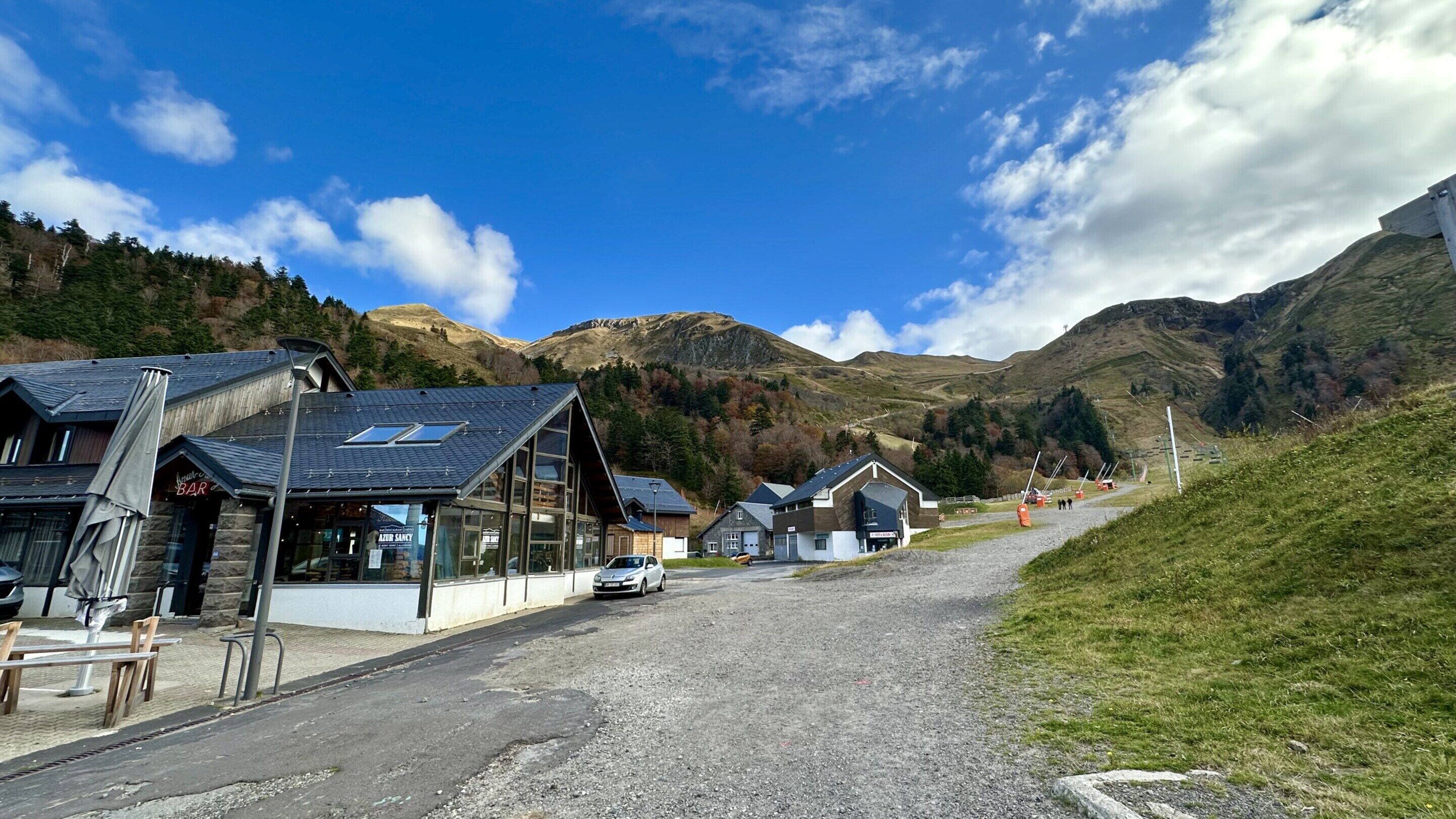 En landevej med huse, en bar og en parkeret bil foran.