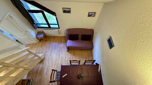 A compact room with a bed, a table, and a window. - Stay by the Hiking Trails (Mont-Dore)