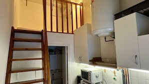 A kitchen with a built-in stove, a wooden ladder, and white cabinets. - Stay by the Hiking Trails (Mont-Dore)