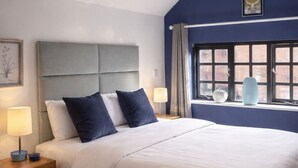 A bedroom with a large bed, a nightstand, a window with curtains, and a ceiling light.