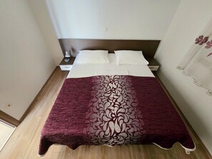 A neatly made bed with white linens and a maroon blanket with a floral pattern. - Costal Apartment for 4 in Zaton (Nin)