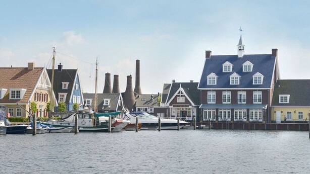 Vista de la costa con edificios tradicionales y barcos amarrados.