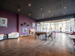Une pièce spacieuse dotée d’un parquet en bois disposé en chevrons, d’un mur d’accent de couleur violette et d’une grande fenêtre laissant entrer la lumière naturelle.