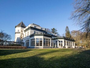 A large, white building with a tower and multiple windows, surrounded by a grassy area and trees. - Discover the Perfect Nature Getaway Close to Burgers Zoo | Swimming Pool (Ellecom)