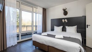 Quarto com uma cama grande, cabeceira escura e decoração com cabeça de animal presa à parede.