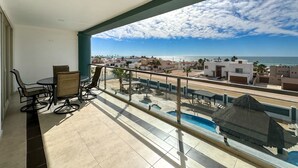 Een balkon met uitzicht op zee en gebouwen.