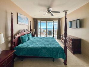 Un dormitorio amplio con una cama grande, un ventilador de techo y vistas al océano.