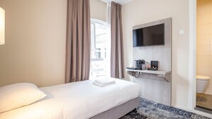 A hotel room with a bed, a mounted TV, a coffee maker, and a small shelf. - Peaceful Retreat with Nature Walks and Local Exploration Near Historic Palaces (Eerbeek)
