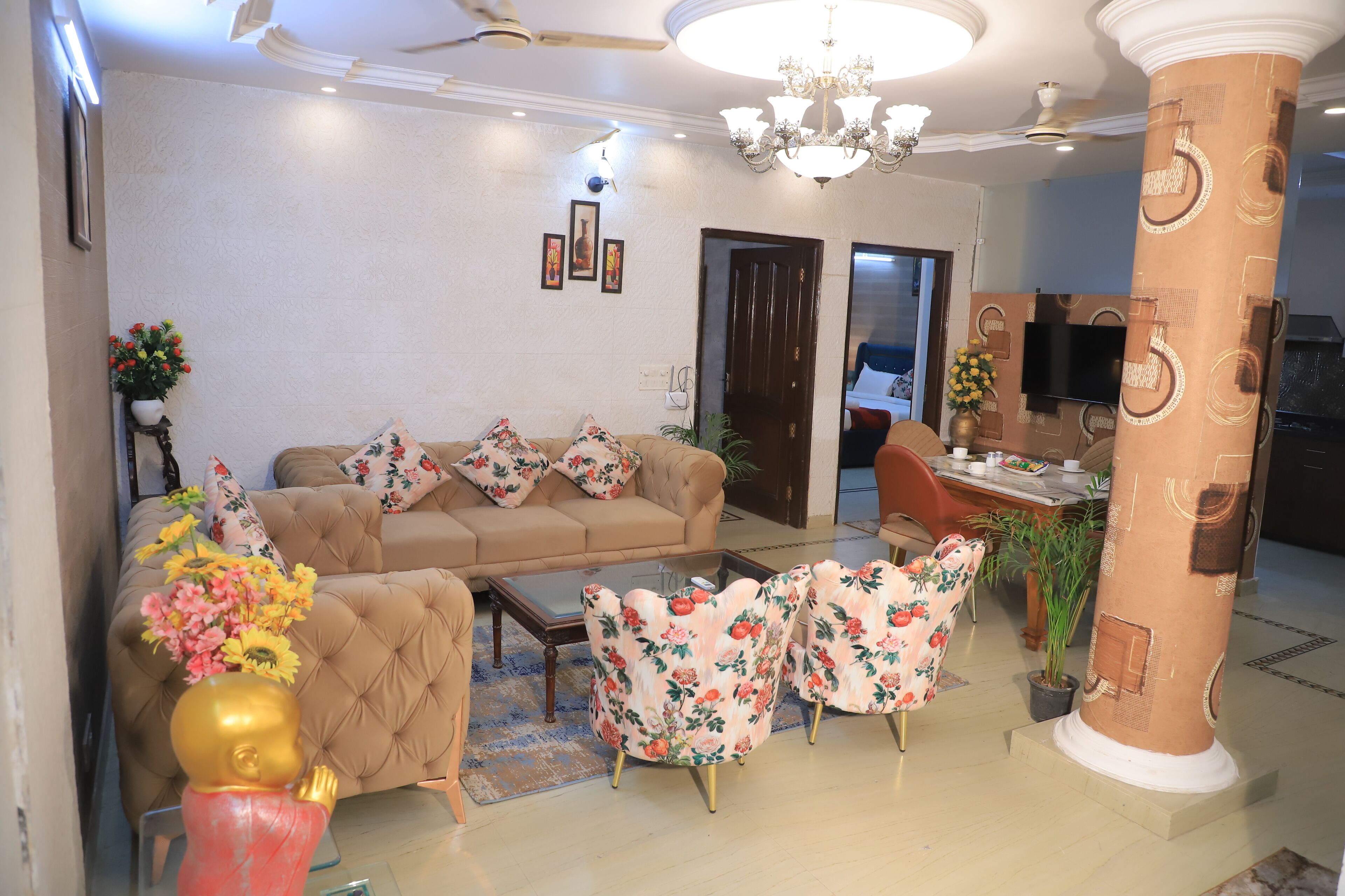 A living room with a sofa, floral armchairs, a coffee table, and a decorative pillar.