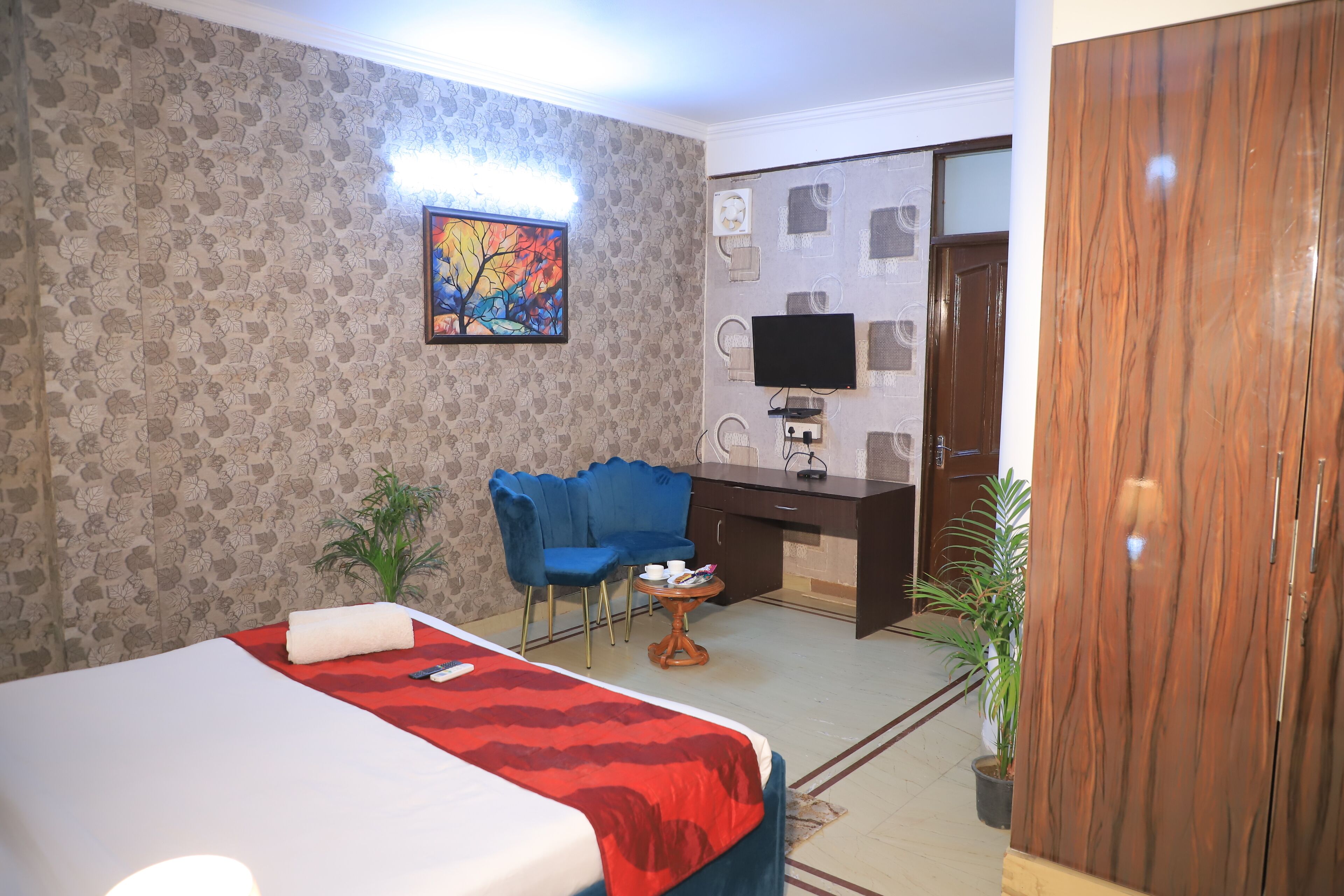 A hotel room with a bed, a desk, a chair, a TV, and a wardrobe.