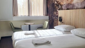 A hotel room with a large bed, two chairs, a small table, and a radiator. - Experience Dutch Nature Up Close — Quiet Stay with Historic Charm, 4 Units (Eerbeek)