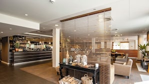 A hotel lobby with a bar area, seating, and a decorative display with plants and candles. - Tranquil Stay with Free Parking, Outdoor Terrace & Biking Adventures (Amersfoort)