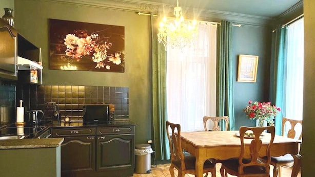 A kitchen with a dining area, wooden cabinets, a microwave, and a chandelier. - Cozy Couple Retreat Near Thermes (Spa)