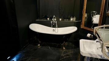 A bathroom with a freestanding bathtub, a vanity with a sink, and a mirror.