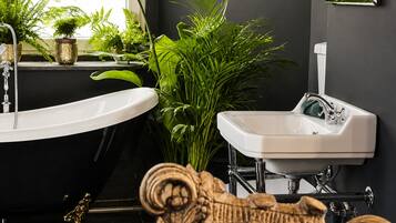 Een badkamer met een bad, een wastafel en decoratieve planten.