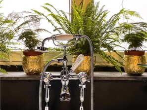 Une salle de bain dotée d’une douche de style rétro, de plusieurs robinets et d’un pommeau de douche à main.
