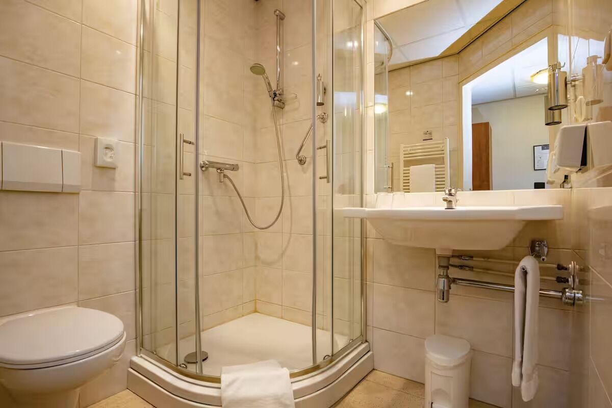 A modern bathroom with a glass-enclosed shower, a white toilet, and a sink with a towel rack.