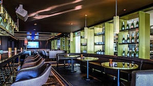Eine Bar mit Sitzgelegenheiten, einem Fernseher und Regalen voller Flaschen.