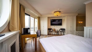 A hotel room with a large bed, a desk with a computer, a TV, and a chandelier. - Recharge by the Sea with Sauna Access! Free Breakfast Onsite! (Vlissingen)