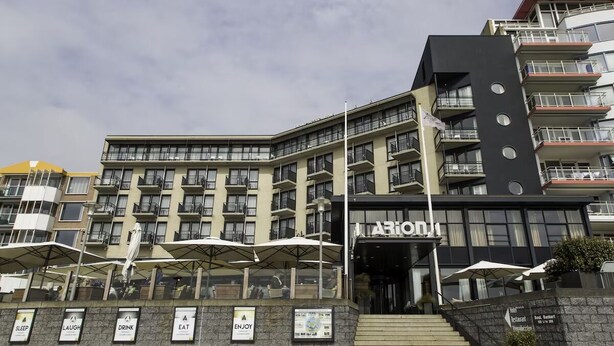 Een hotel met meerdere verdiepingen, terras en een opvallende ingang.