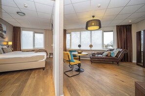 A modern hotel room with a bed, a sofa, a dining table, and a large window. - Scenic Escape with Complimentary Breakfast, Parking and Local Trails (Middelburg)