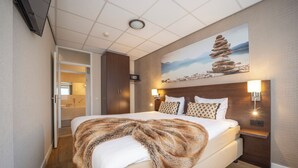 A modern hotel room with a large bed, a painting of a rock formation, and a view of a bathroom. - Scenic Escape with Complimentary Breakfast, Parking and Local Trails (Middelburg)
