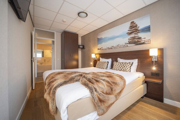 A modern hotel room with a large bed, a painting of a rock formation, and a view of a bathroom. - Scenic Escape with Complimentary Breakfast, Parking and Local Trails (Middelburg)