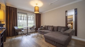 A modern living room with a sectional sofa, a dining table with chairs, and a large window with curtains. - Comfortable Retreat: Free Breakfast, Parking & Cycling-Friendly Location (Middelburg)